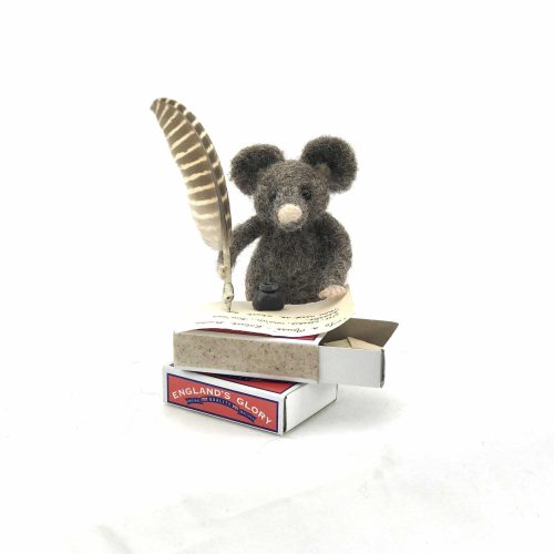 a card design of a needle-felted mouse writing with a feather quill at a table made from a matchbox